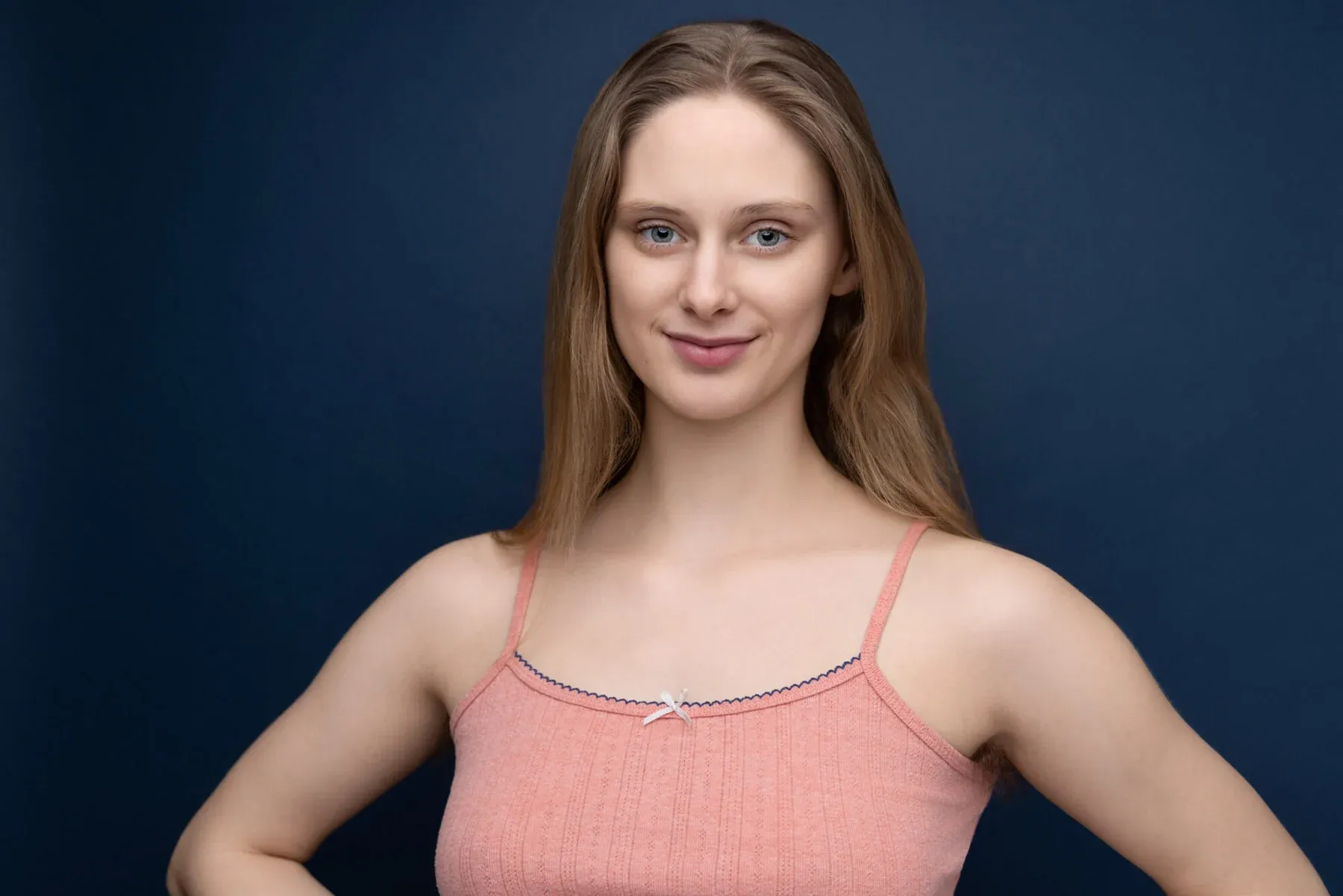 Cordelia June Reynolds in a pink camisole against a navy backdrop, hands on hips