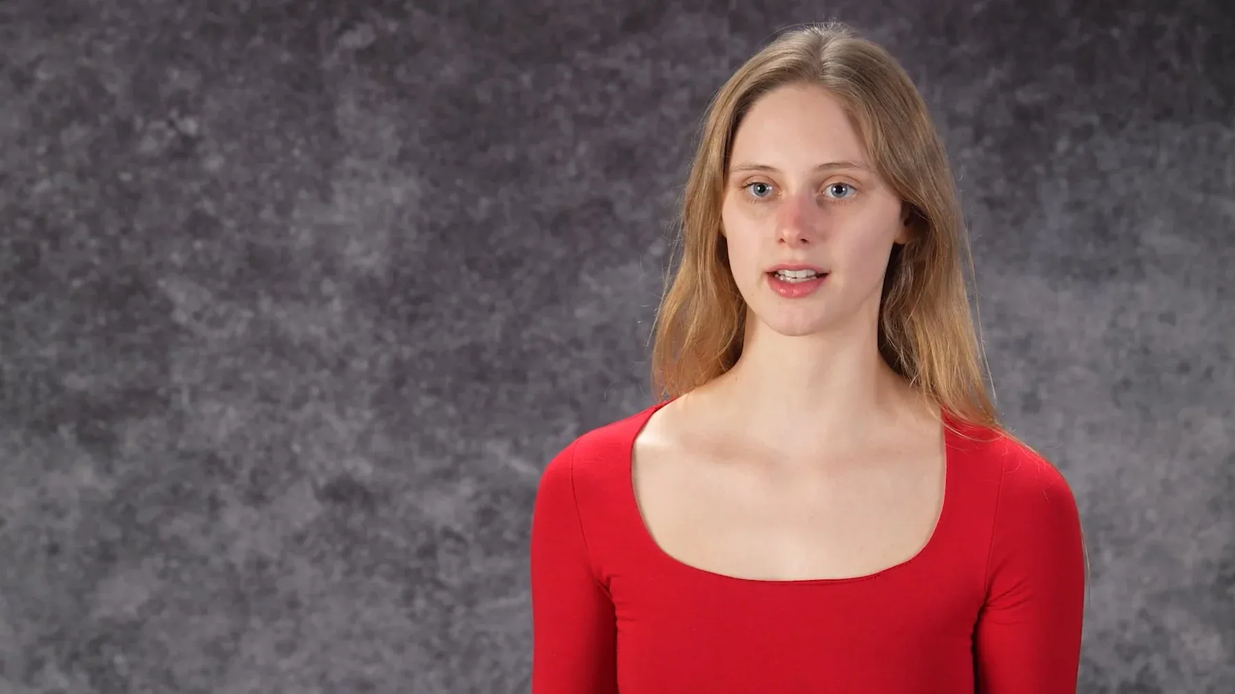 Cordelia June Reynolds mid speech in a red top against a grey backdrop