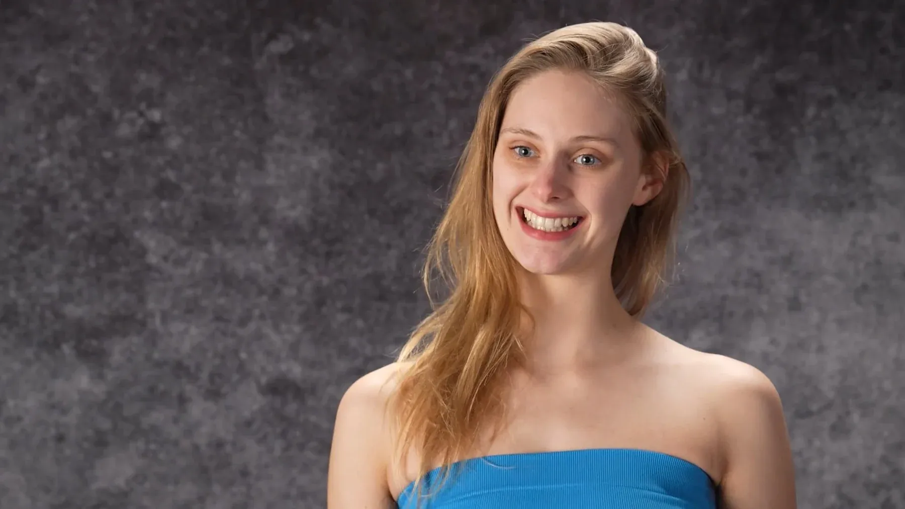 Cordelia June Reynolds laughing in a blue top against a grey backdrop
